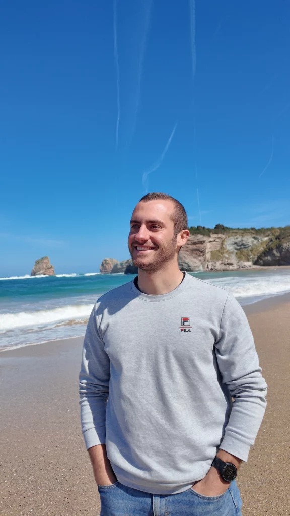 Nutritionniste de face sur une plage de sable avec en arrière plan une falaise, l'océan et le ciel bleu